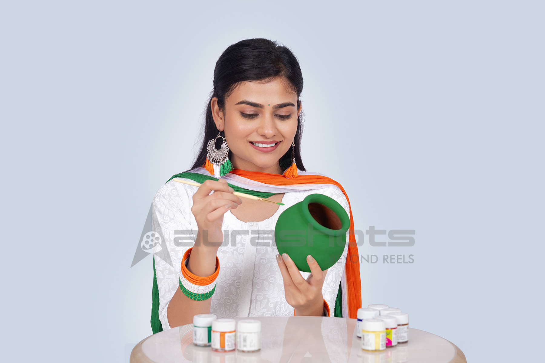 Indian woman colouring an earthen pot and tricolor ribbons