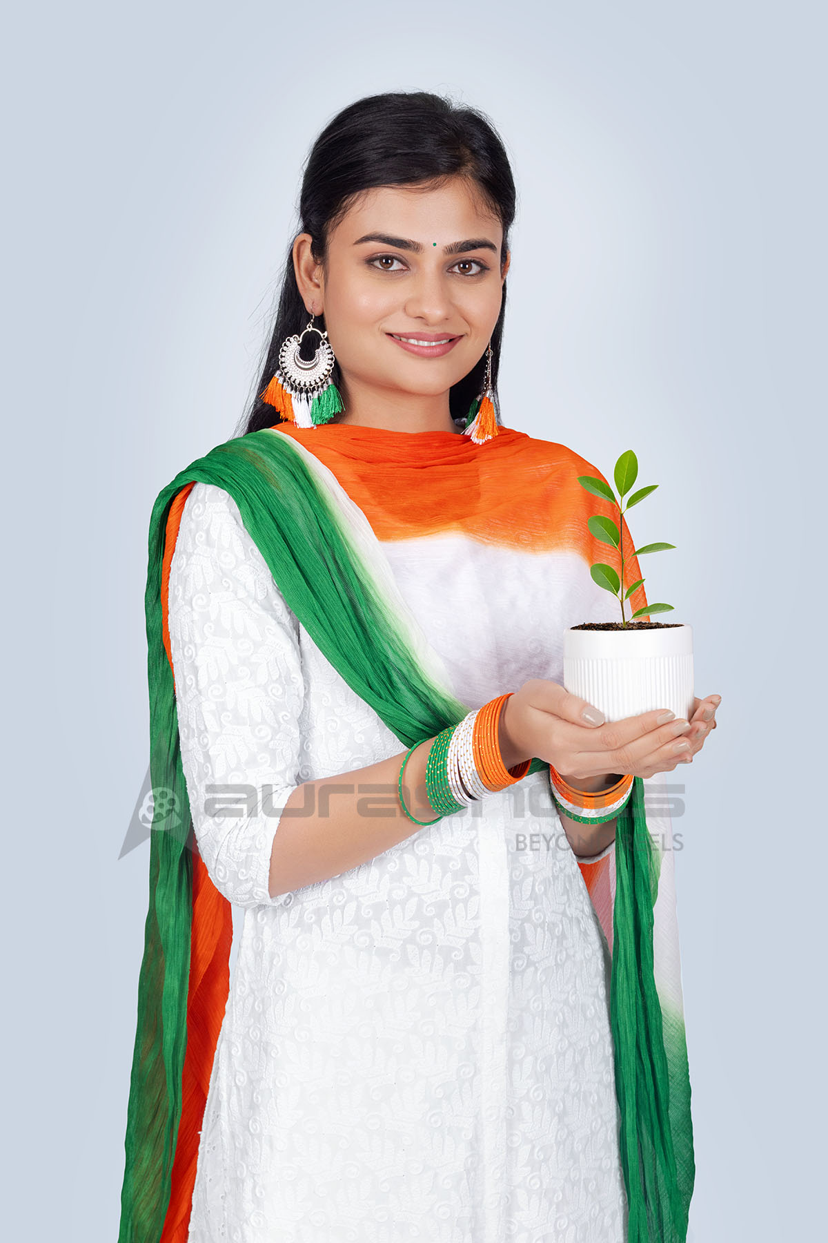 Indian woman in tricolor scarf holding a nursery plant