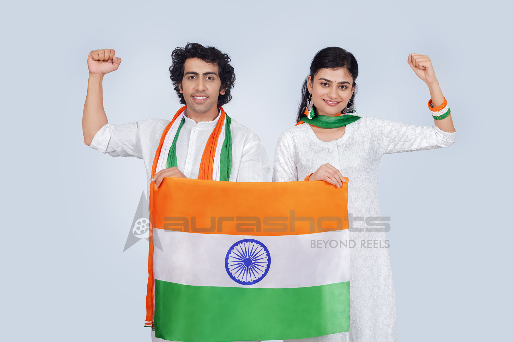 Indian couple raising fists in celebration with national flag