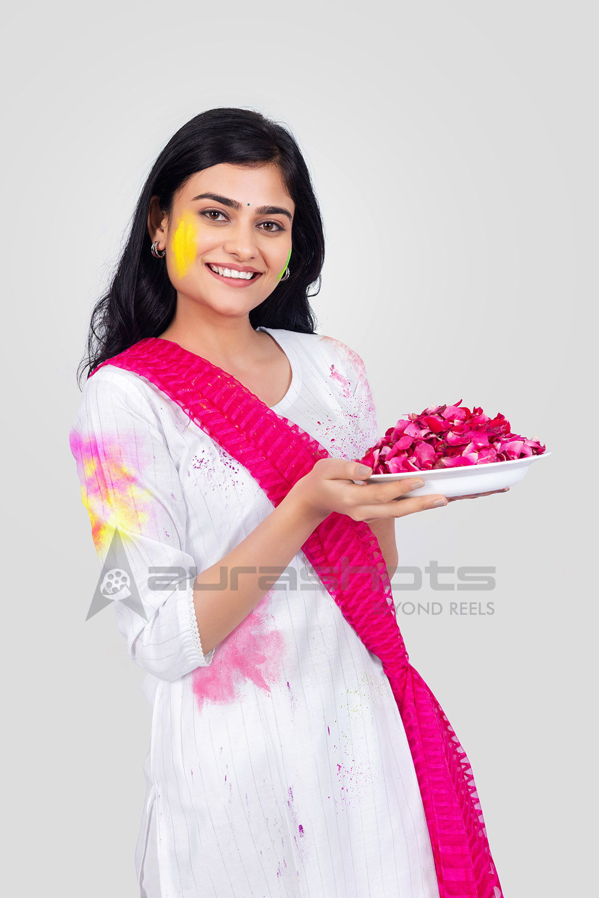 Indian woman holding a plate of rose petals during Holi celebration