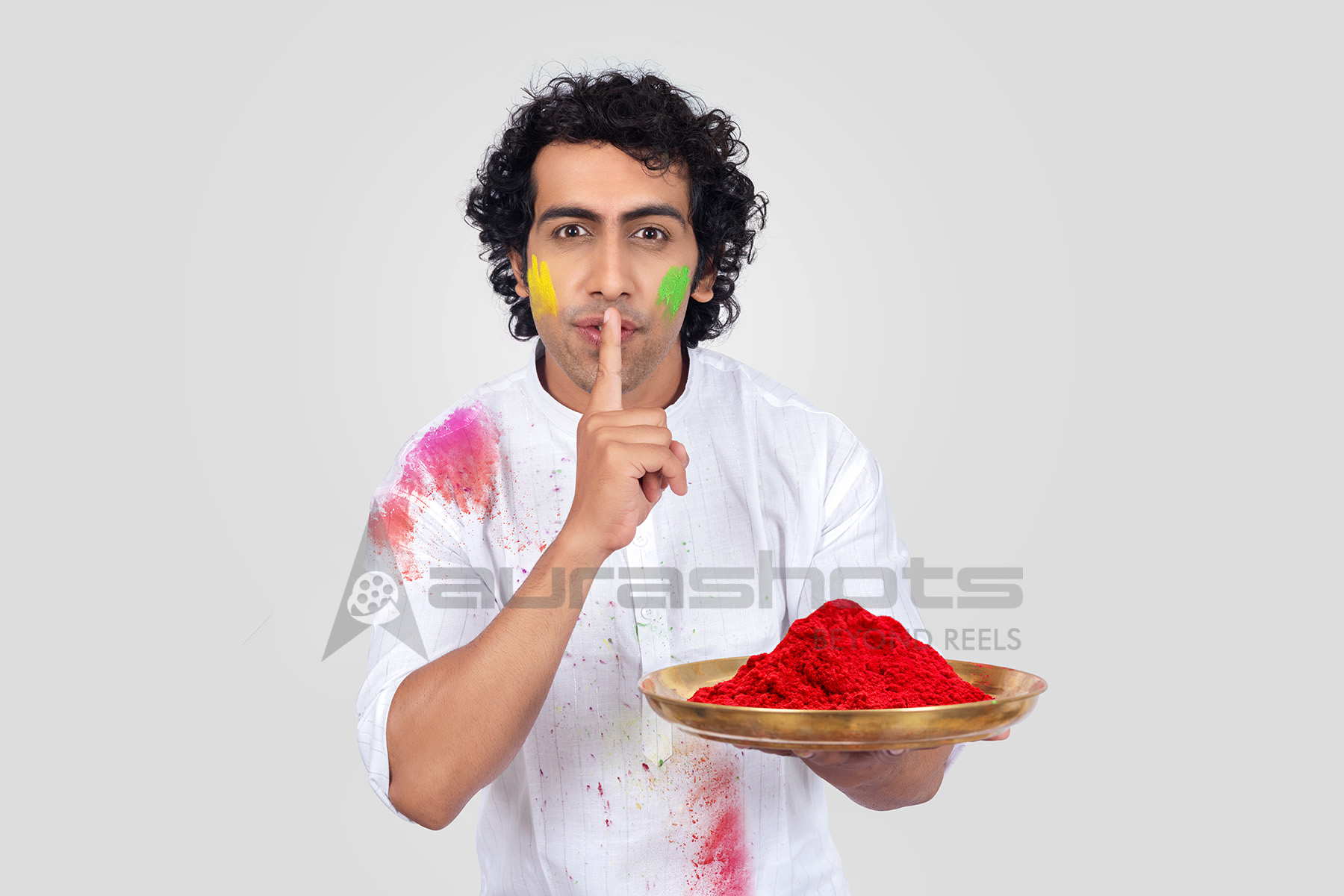 Indian man holding a plate of gulal during the Holi celebration