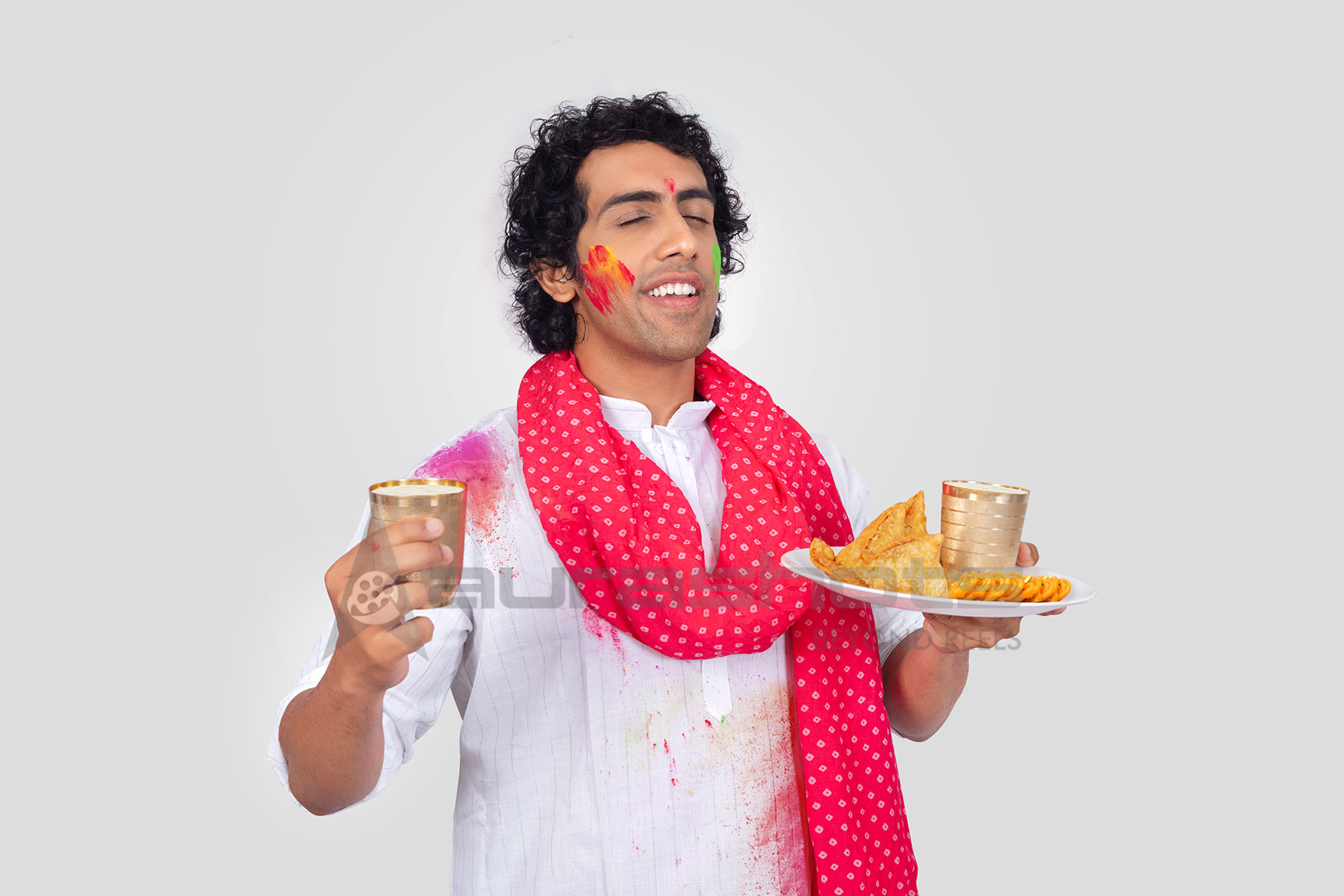 Indian man celebrating Holi with traditional Indian snacks and drinks