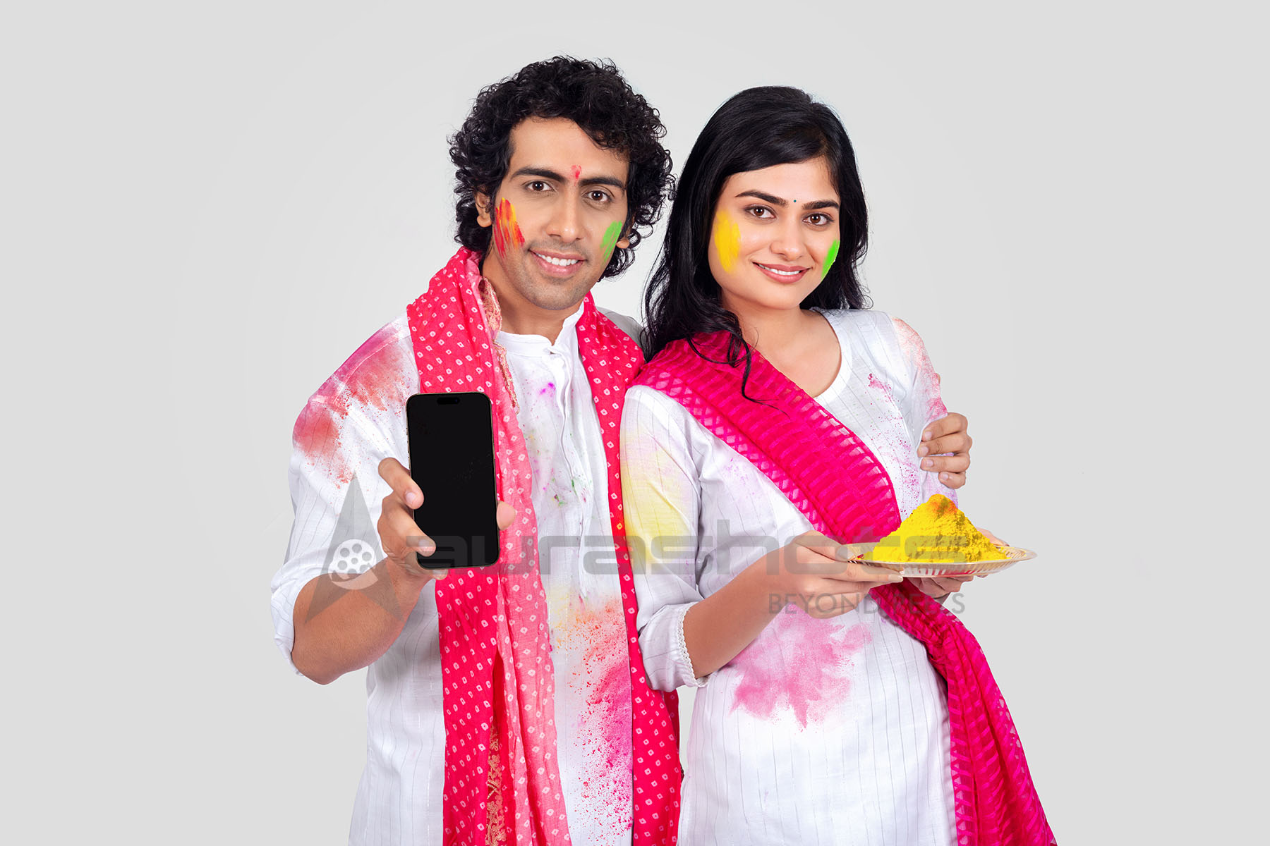 Couple posing with colors and a mobile phone for Holi