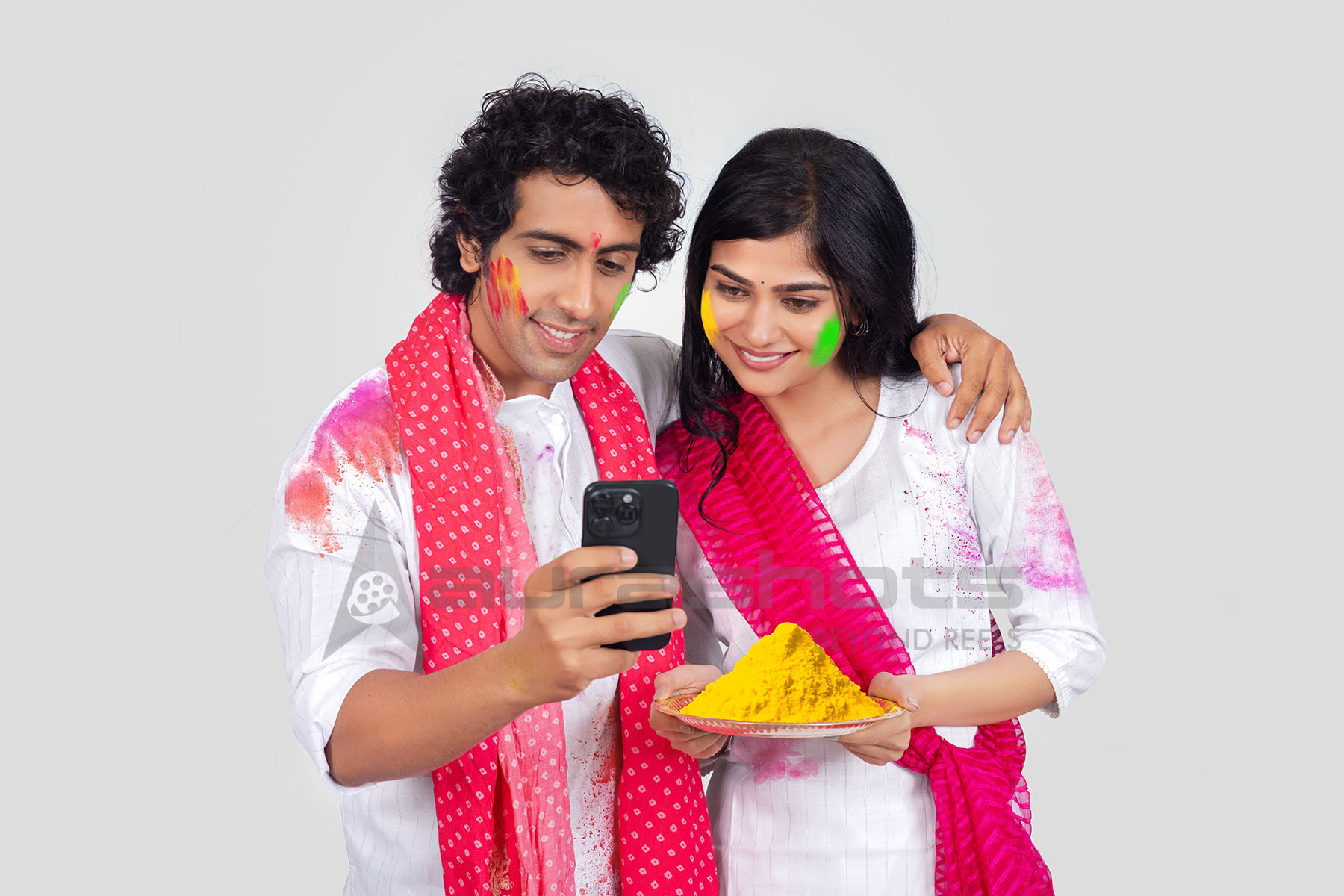 Couple smiling and checking phone during Holi