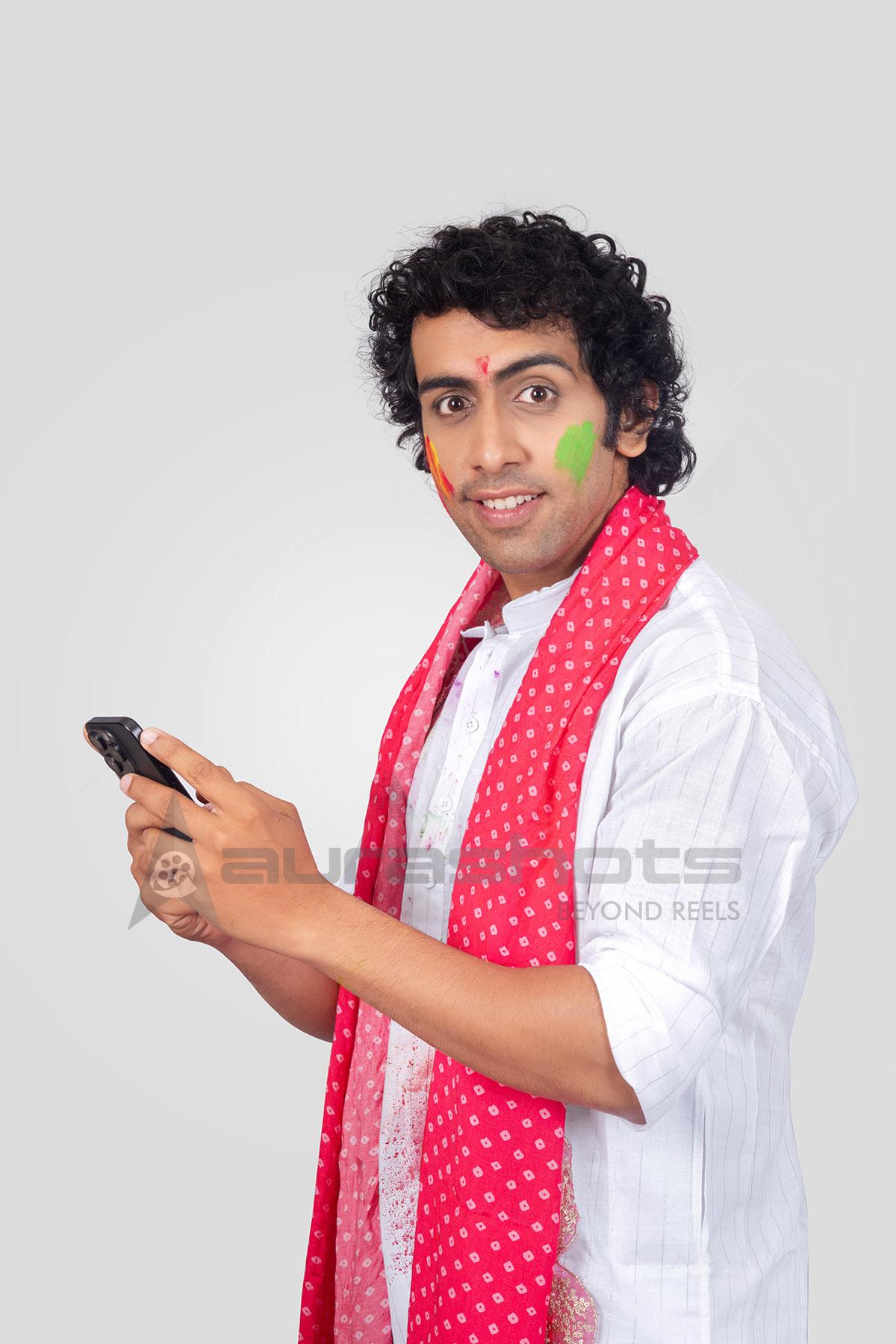 Indian man celebrating Holi using smartphone