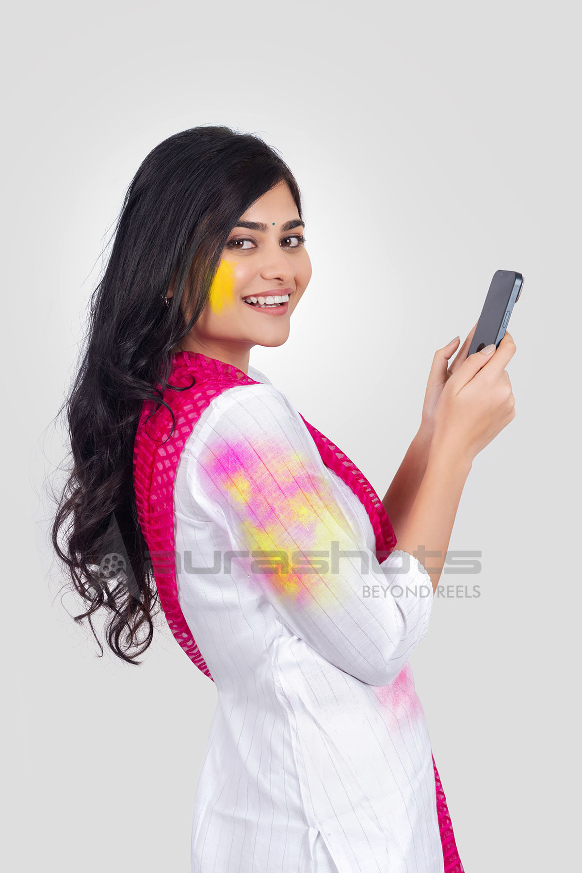 Indian woman celebrating Holi using smartphone