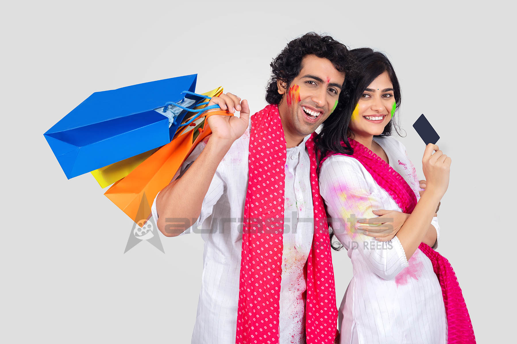 Couple holding shopping bags and a credit card for festive Holi shopping