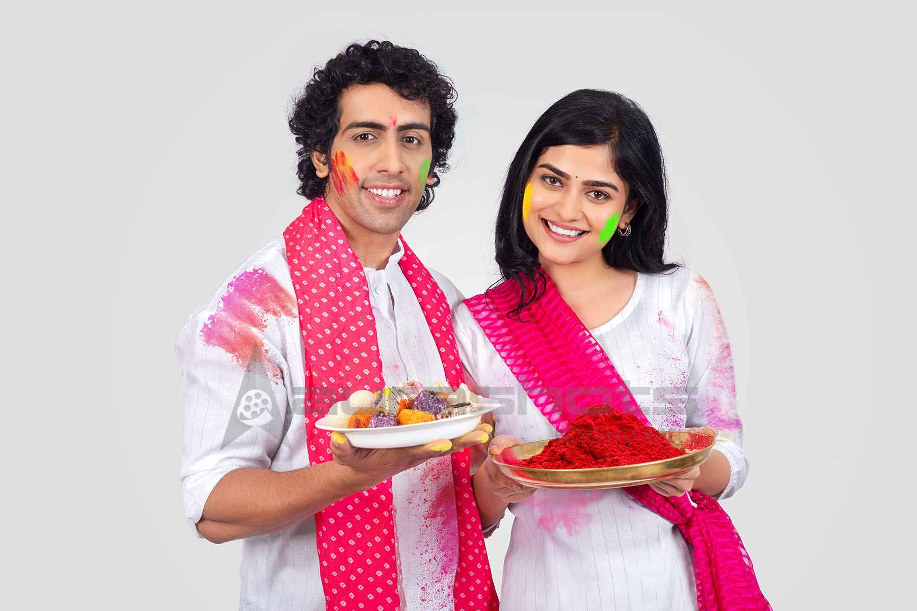 Couple holding a sweets plate and colours for the Holi celebration