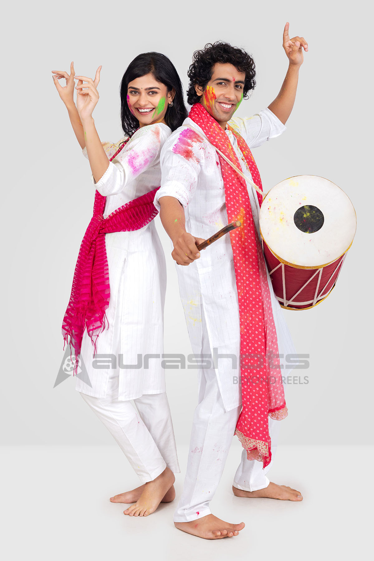 Couple posing with dhol in white festive attire