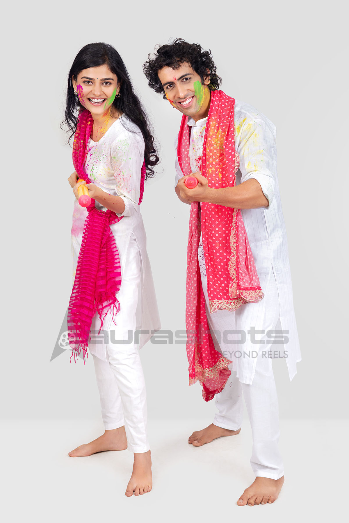 Couple posing cheerfully with pichkari for Holi celebration
