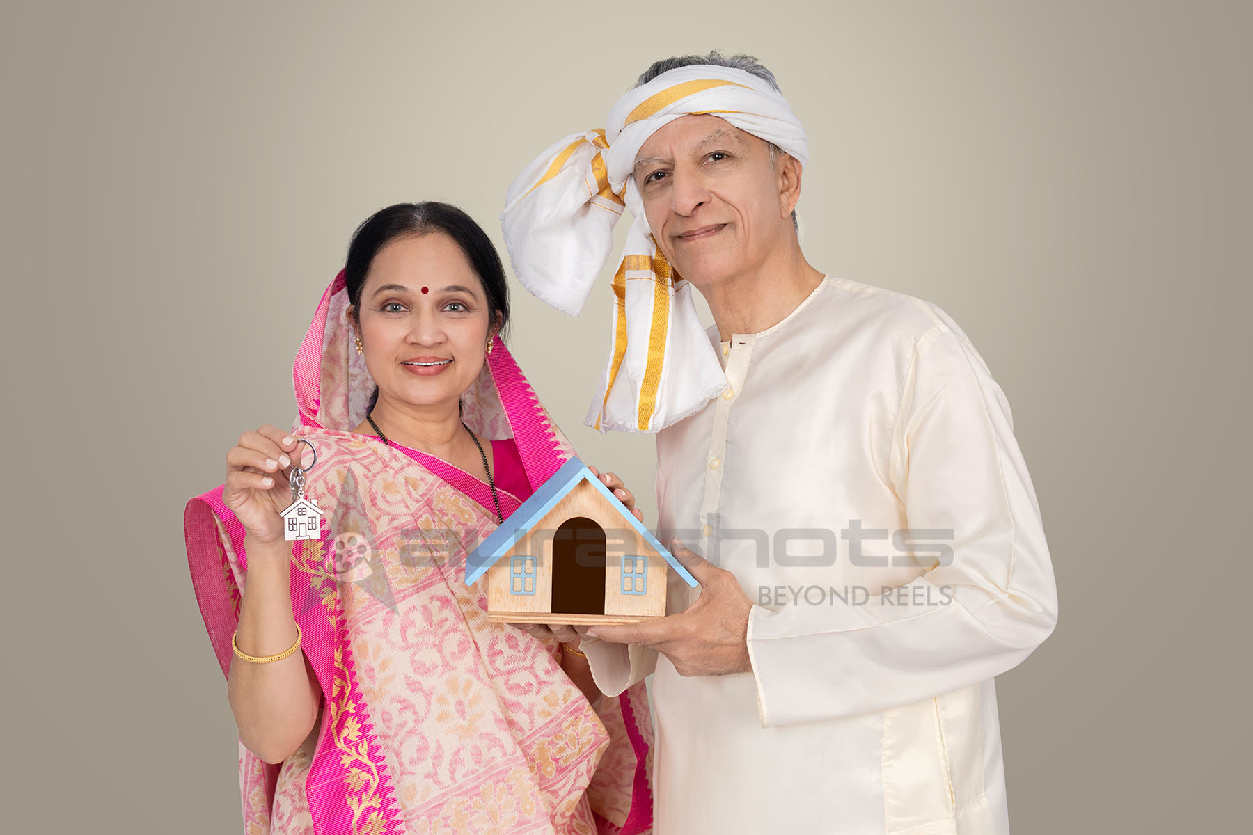 Rural Indian senior couple with house model representing home loan support
