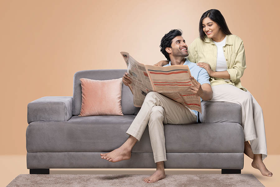 Indian couple on sofa reading newspaper together