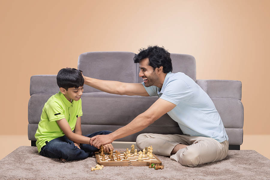 Young Indian father teaching chess to his son