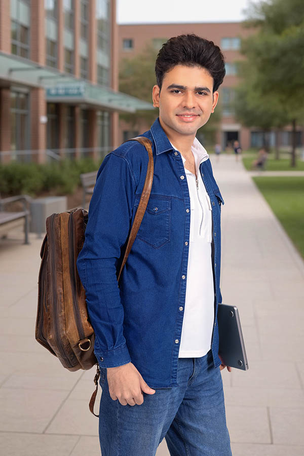 Confident Indian student walking on university campus pathway