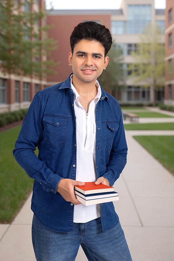 Indian male college student holding books and smiling confidently