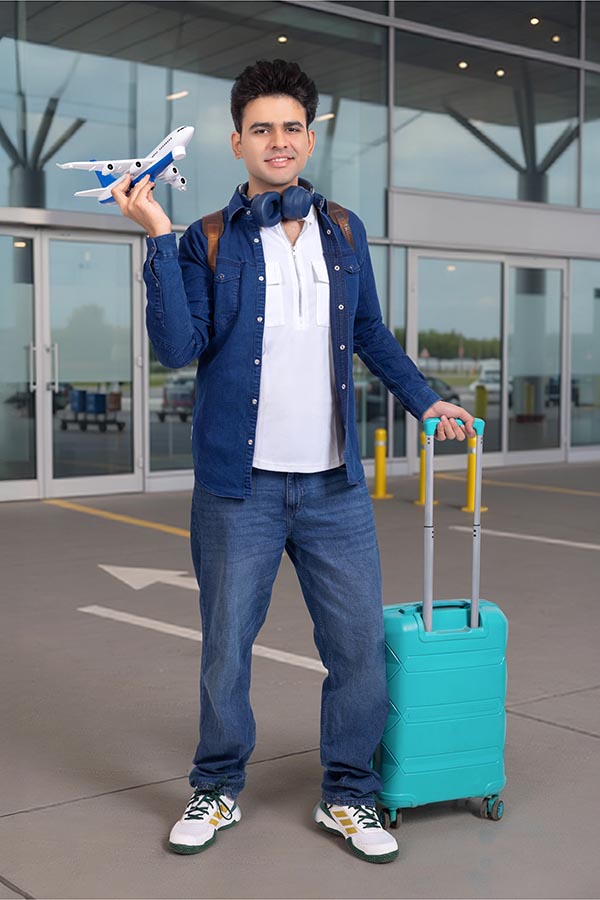 Indian student traveler pulling suitcase inside airport terminal