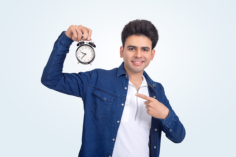 Indian college student pointing at alarm clock in studio setup