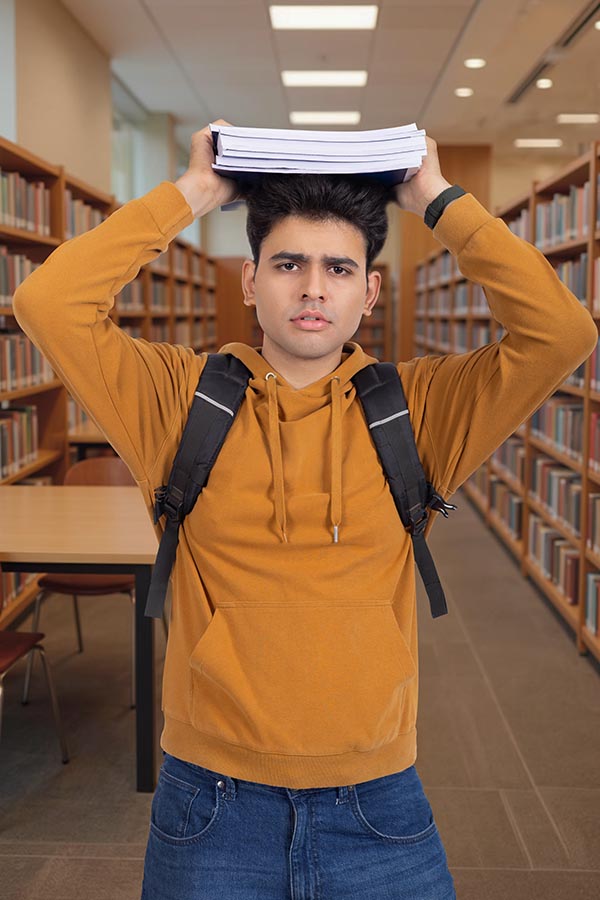 Stressed Indian college student expressing study pressure in library
