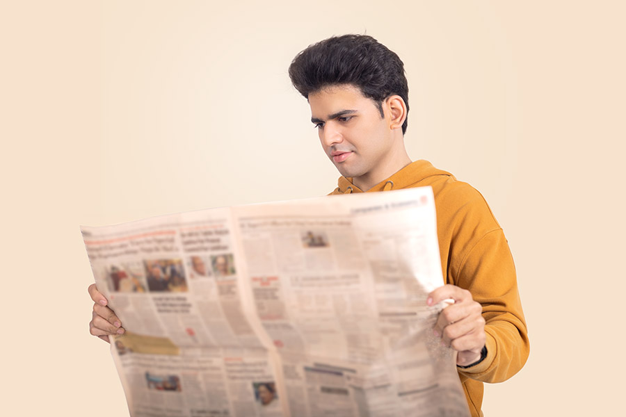 Indian young man reading newspaper in casual indoor portrait