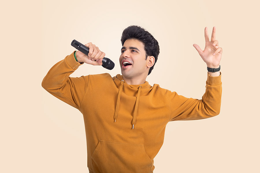 Young Indian man singing with microphone in energetic pose