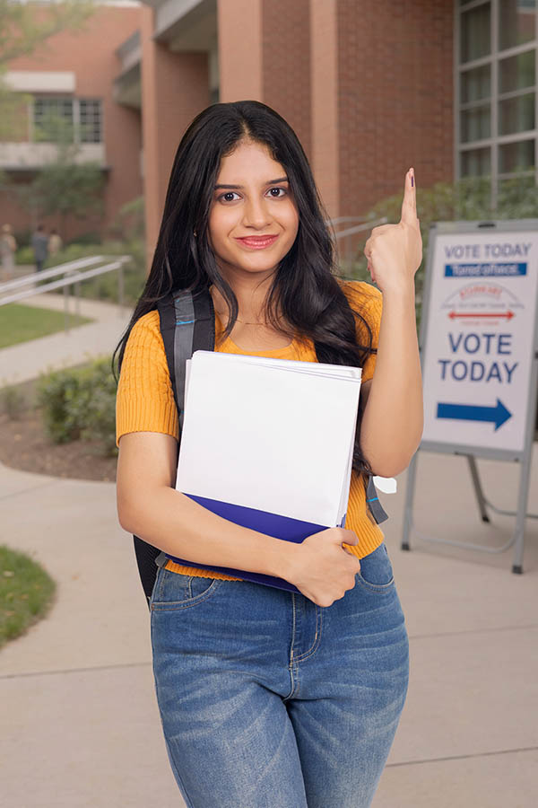 Young Indian college girl showing inked finger after voting on campus