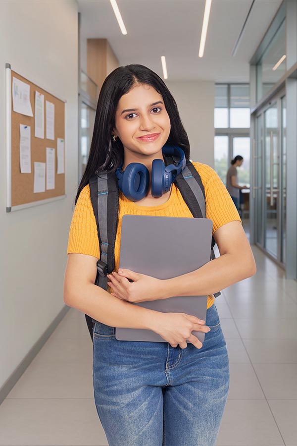 Confident Indian teenage girl with headphones holding laptop