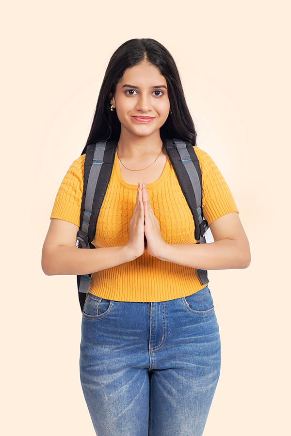Indian college girl doing namaste greeting with backpack