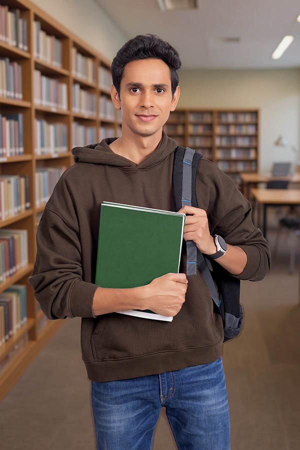 Indian male student holding notebook inside university library