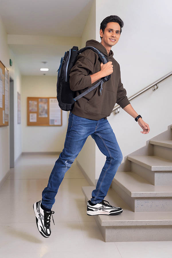 Young Indian male student climbing stairs in college campus corridor