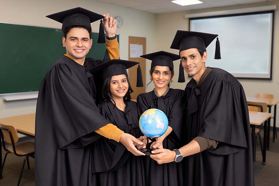 Group of Indian graduates holding globe during convocation ceremony