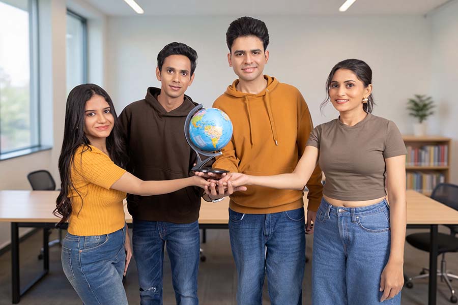 Diverse Indian college students holding globe together in classroom