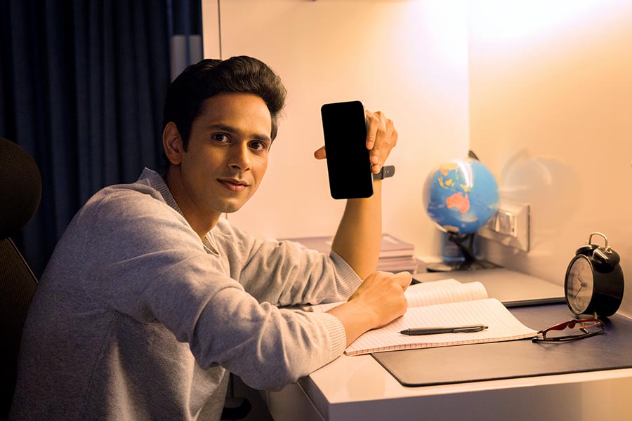 Indian student showing smartphone while studying at night