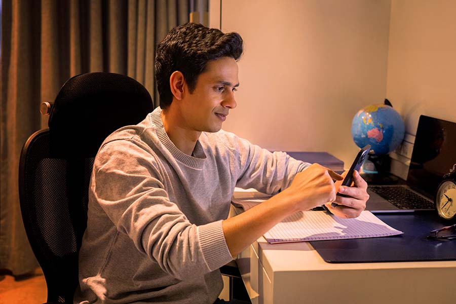 Indian student using smartphone during night study session