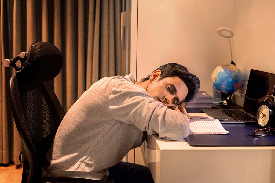 Young Indian student sleeping on study desk at night