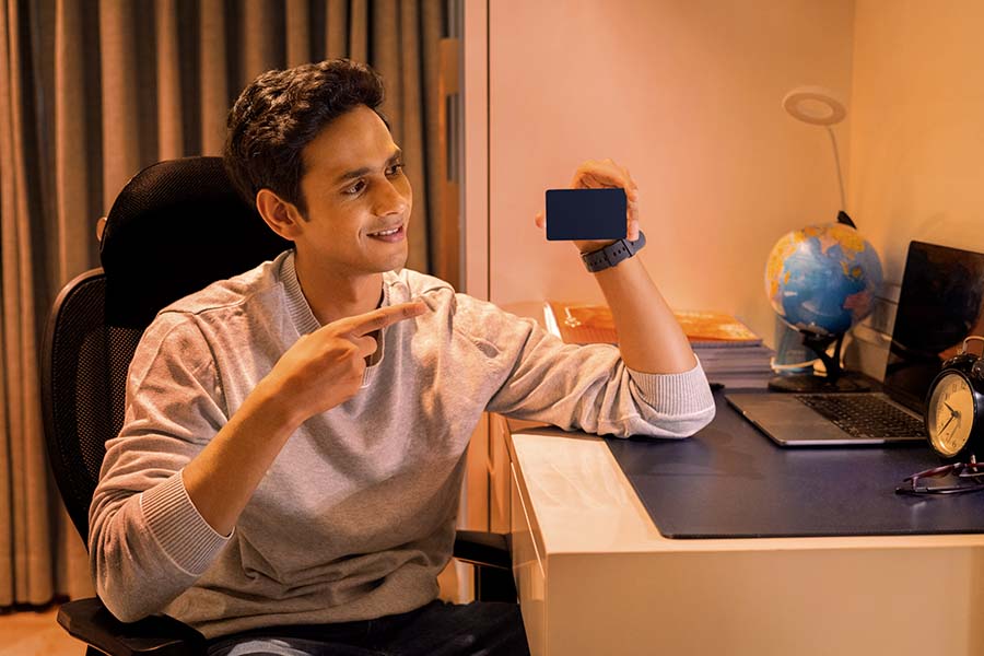 Young Indian student showing blank card at study desk