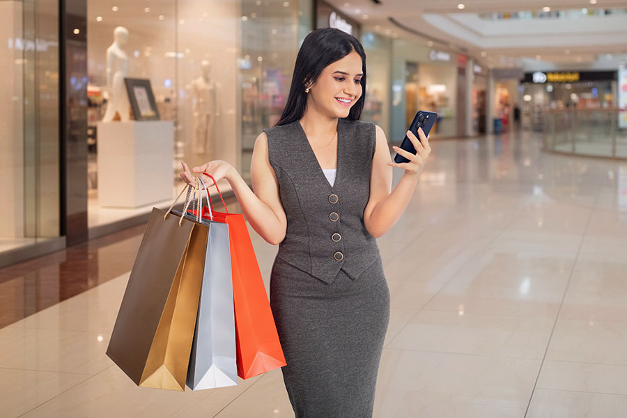 Indian woman shopping while using smartphone in mall