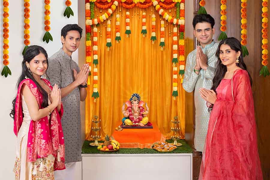 Indian family performing Ganesh puja with folded hands at home