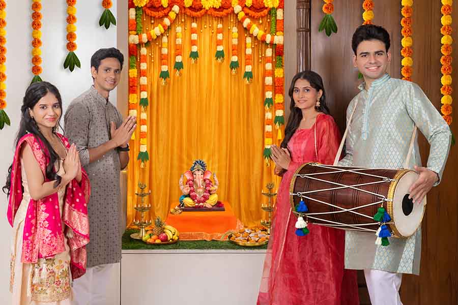 Indian family celebrating Ganesh Chaturthi with dhol and prayers at home