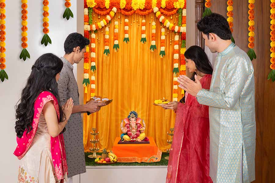 Family praying together in front of Ganesh idol during home celebration