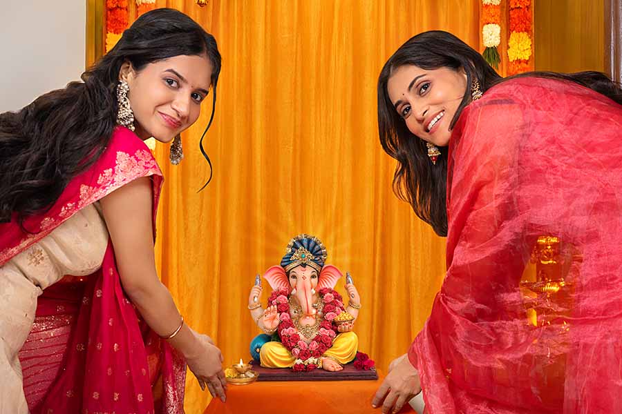 Women performing Ganesh puja ritual with idol at home close up