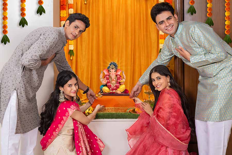 Group of friends celebrating Ganesh Chaturthi with prayers at home