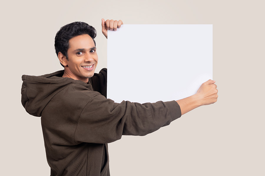 Smiling Indian man showing blank signboard from behind