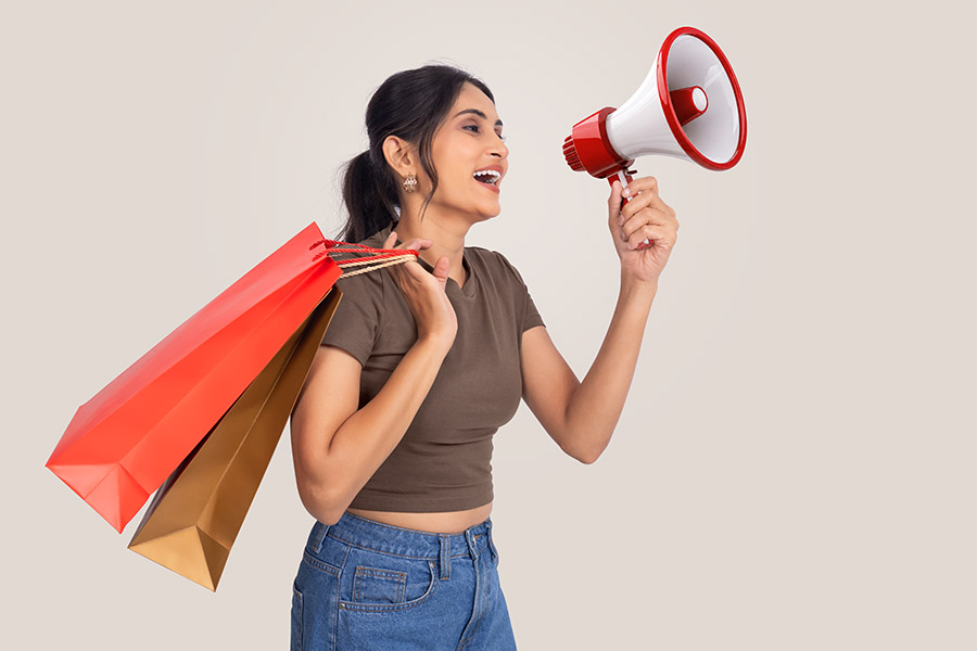 Female shopper announcing sale with megaphone and shopping bags