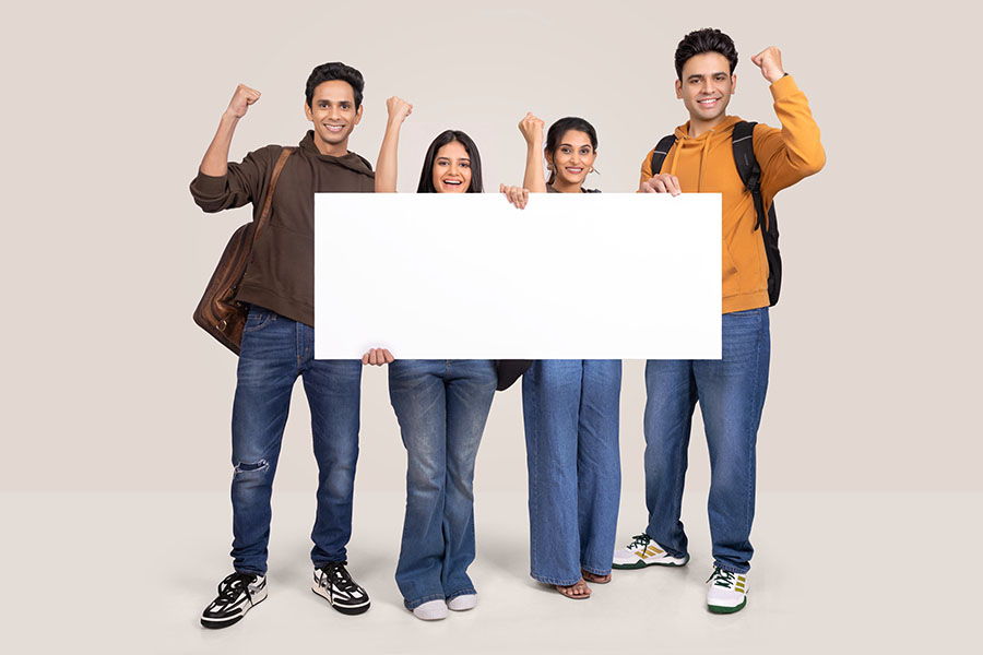 Group of Indian college students celebrating success with blank banner