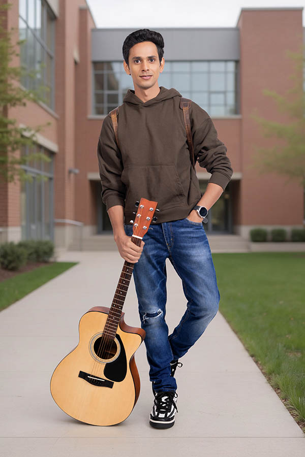 Young Indian college student with guitar on campus walkway