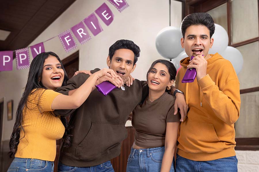 Young friends celebrating party with chocolates and cheerful expressions