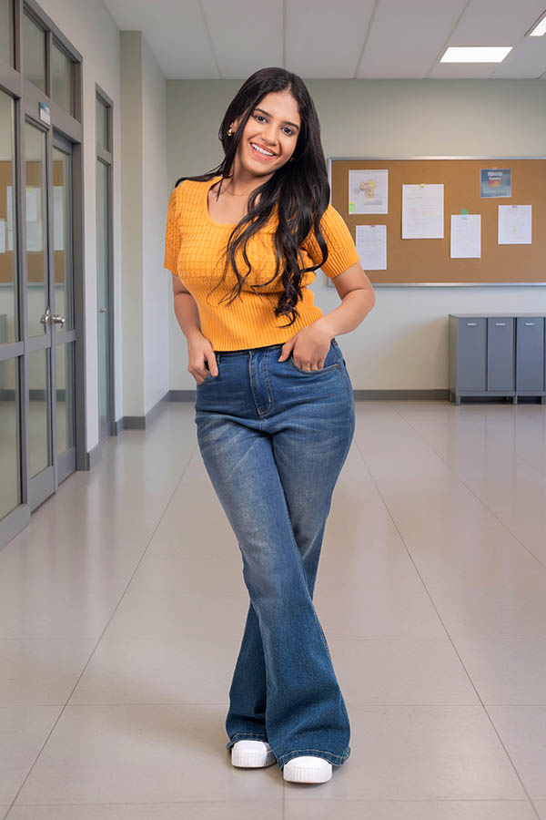 Smiling young female student posing in educational institution corridor