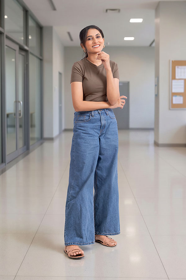 Confident young woman standing thoughtfully in college corridor