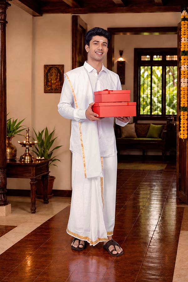 Young Indian man carrying festive gift boxes for Onam celebration
