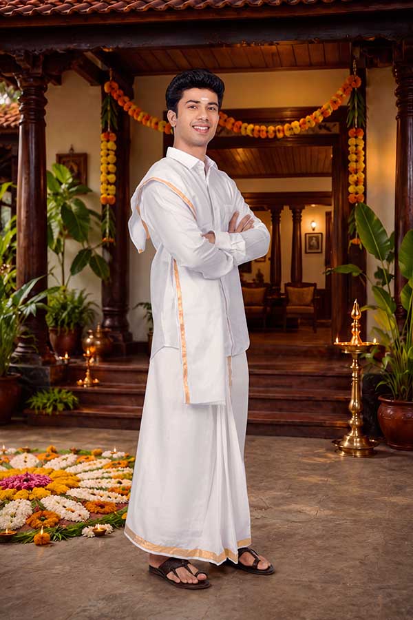 Confident young Indian man posing in traditional Kerala outfit for Onam
